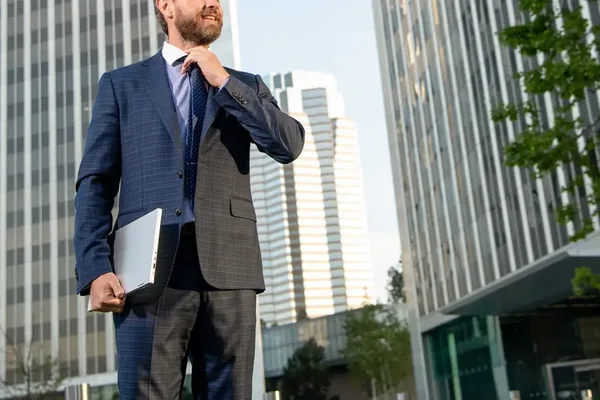 Préstamos de capital privado para autónomos: autónomo con su portátil entre edificios de oficinas